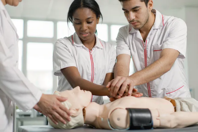 Estudiantes practicando reanimación cardiopulmonar con un maniquí